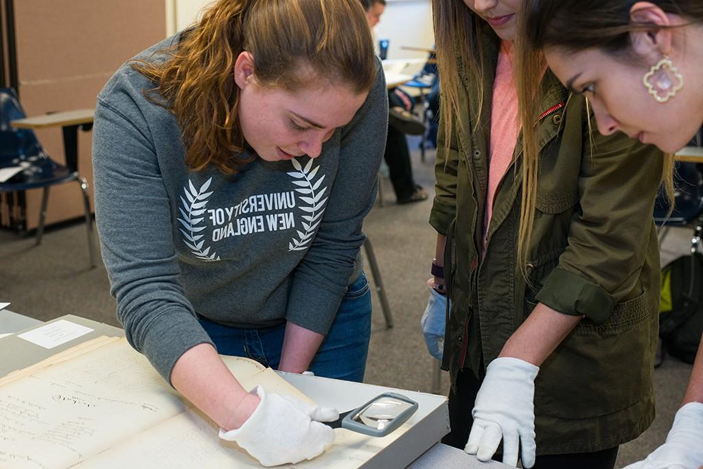 学生 using a magnifying glass to look at historical U N E documents