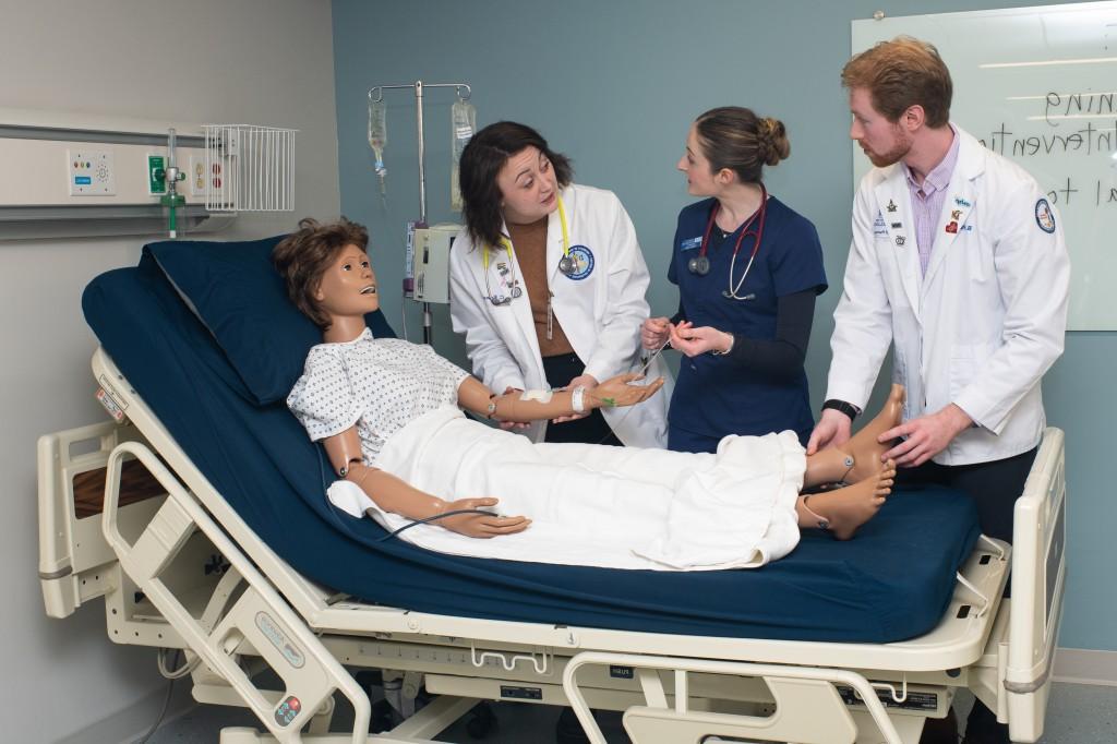 两名医学专业的学生和一名护理专业的学生一起在一个模拟病人身上实习
