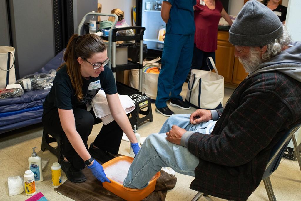 A student washes a man's feet at Milestone Recovery in Portland, ME