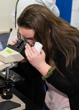 一名学生在北大脑科学展上通过显微镜观察