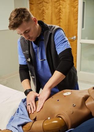 一个学生在实验室里按压病人模拟器的胃