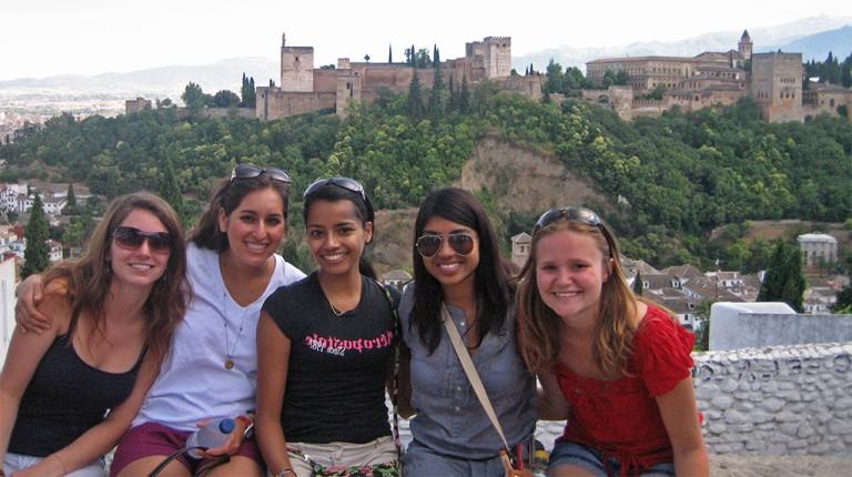 A group of students sitting in front of a cityscape in Spain