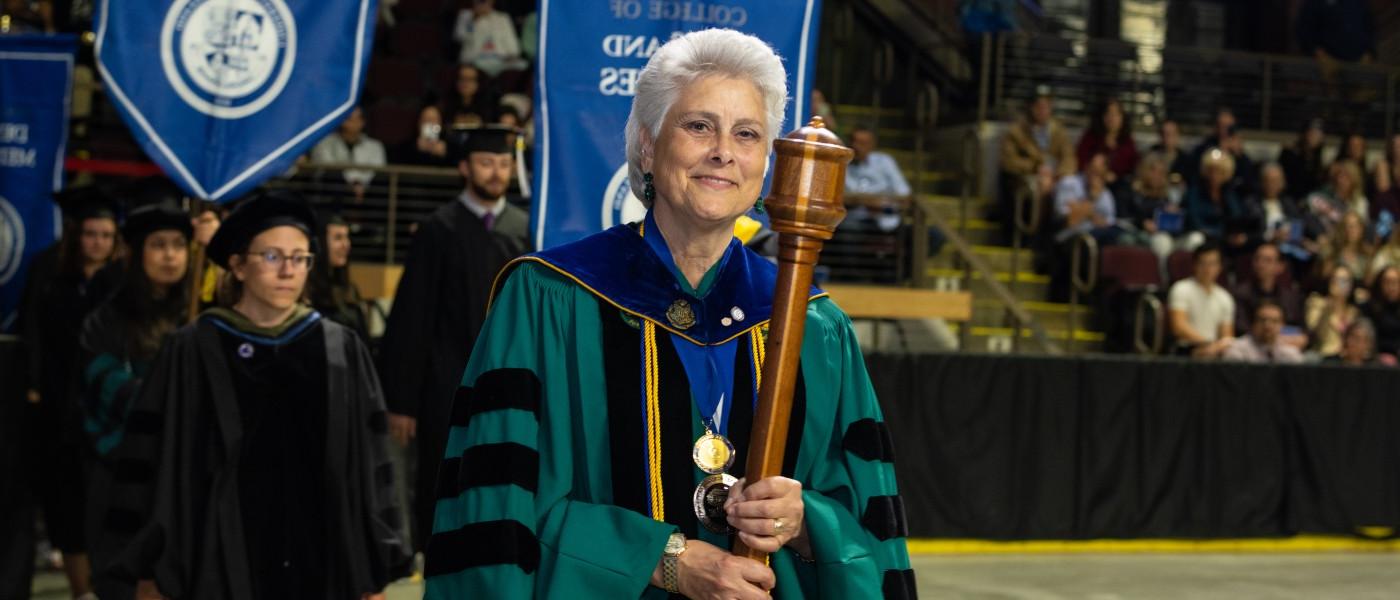 教授. Marilyn Guggliuci拿着大学的徽章