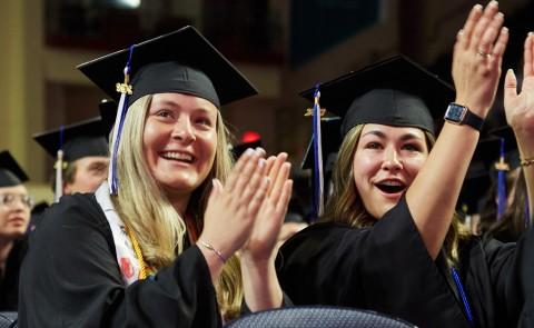 两位毕业生在大学毕业典礼上鼓掌欢呼 