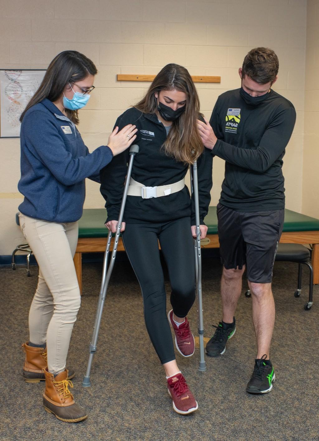 Two Physical Therapy students practice assisting a patient with new crutches