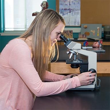 A Biological Sciences student looking through a microscope