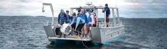 A group of students on a U N E boat retreive a white shark buoy from the ocean